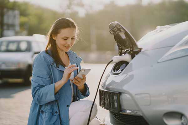 Electric Vehicle Woman Calculates Savings from No Carbon Offsets Electric Vehicle Woman Calculates Savings from No Carbon Offsets