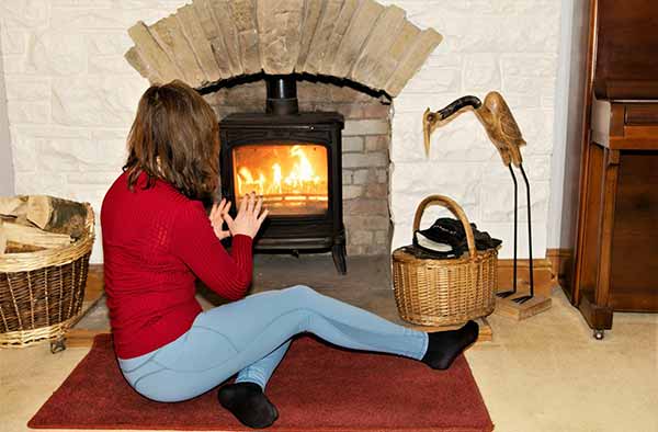 Fuel Costs Conservation | Woman Sits in Front of Fireplace