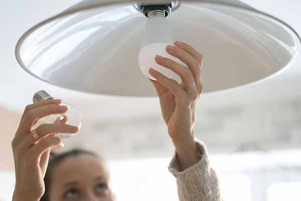Lady Installing Light Bulb | Household Benefit from EE Program