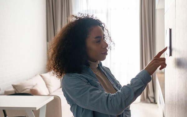Woman Adjusts Heating Thermostat to Lower Energy Costs