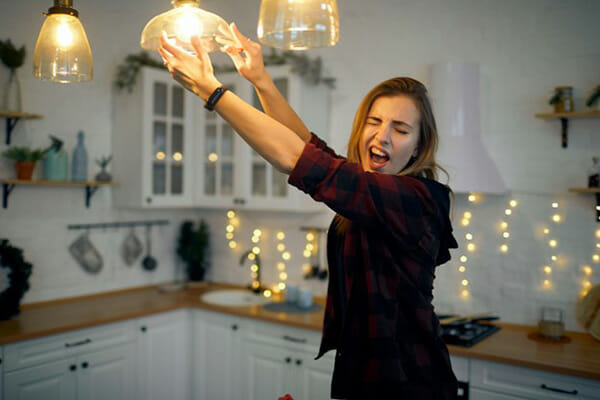Woman Installs Energy-Efficient Light Bulb Woman Installs Energy-Efficient Light Bulb