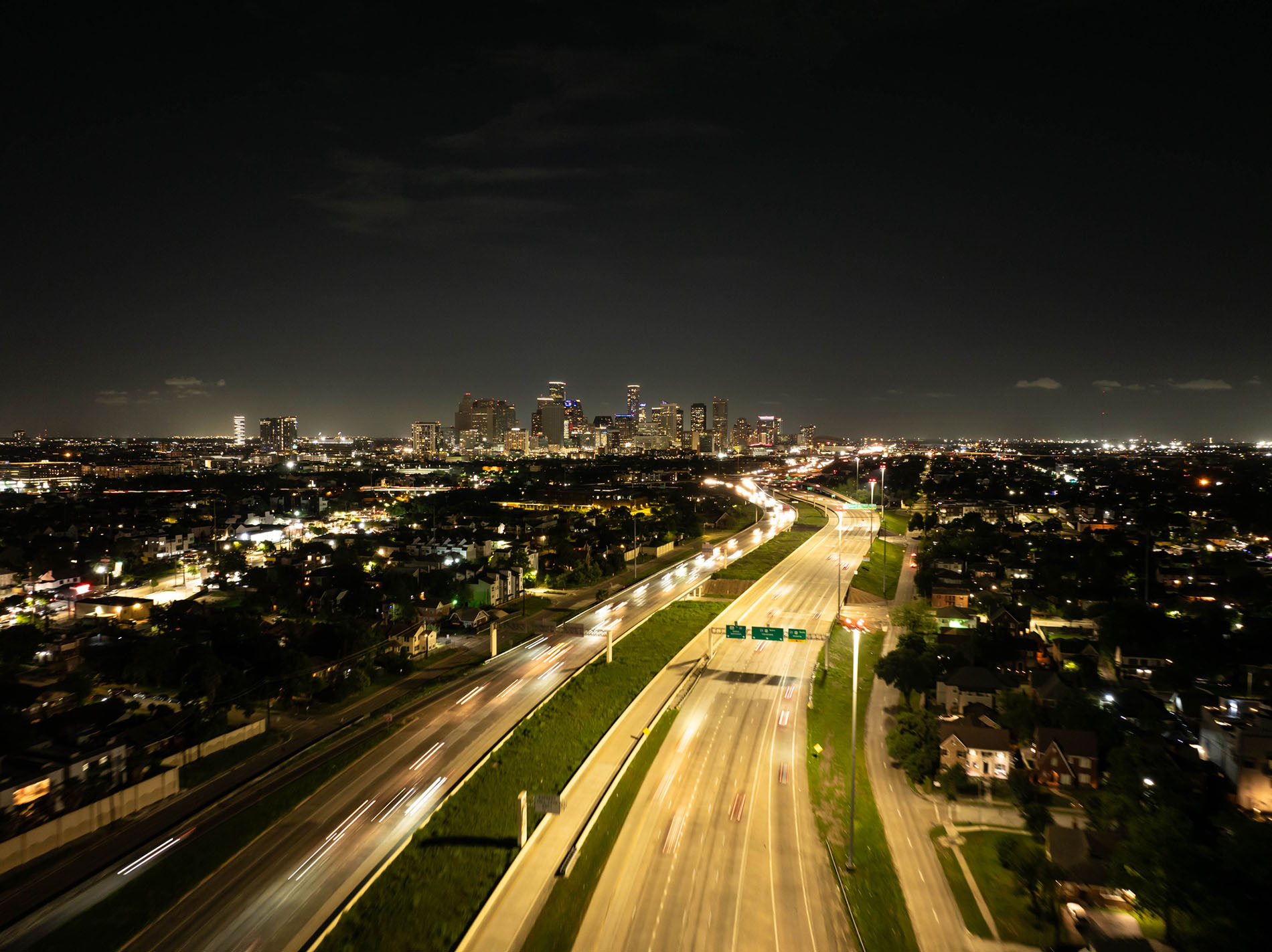 Vibrant light trails from cars zooming along the highway illuminate the downtown Houston skyline at night, capturing the dynamic urban energy the future of texas' power nighttime highway image of cars racing