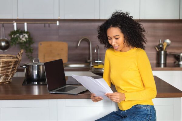 a woman in a kitchen looking at her energy bills