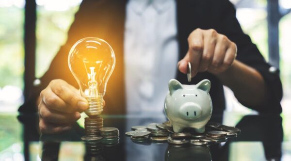 A man holding a piggy bank and a lightbulb