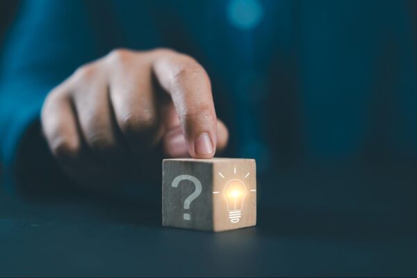a person with their hand on a cub with a question mark on it