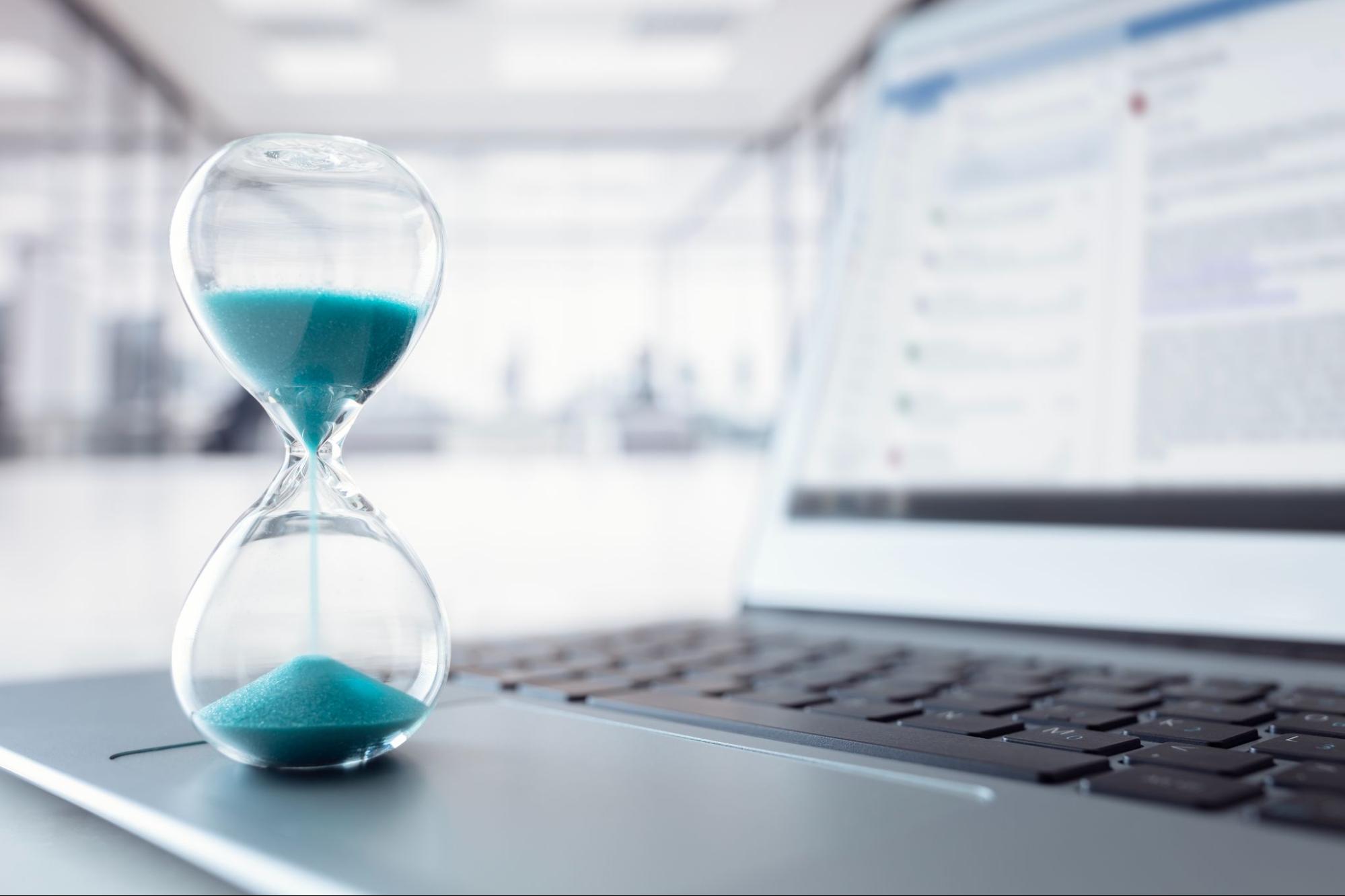 an hourglass sitting next to a laptop