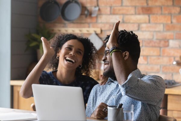 two people sitting in front of a laptop celebrating