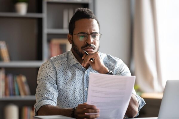 A man holding a piece of paper in his hands, reading