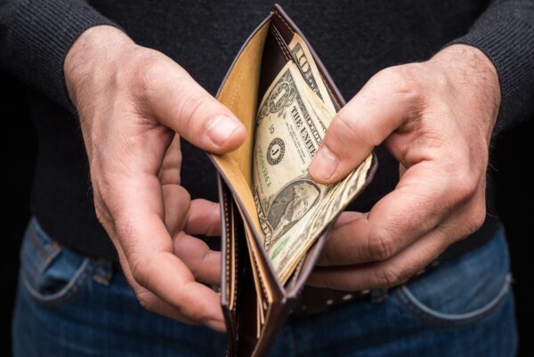 A person opening their wallet looking at dollar bills